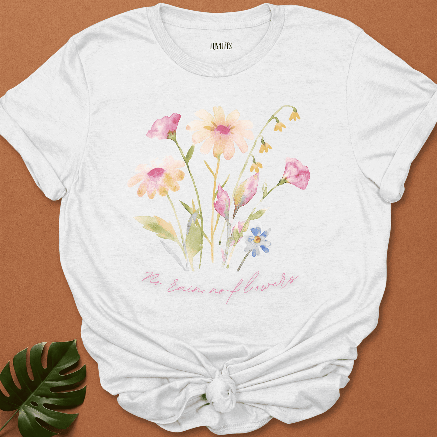 White t-shirt with floral design and text on a brown background